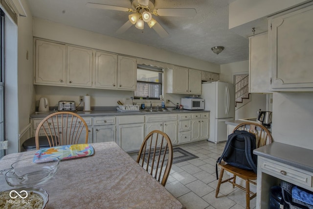 kitchen with white appliances, ceiling fan, a textured ceiling, and a sink