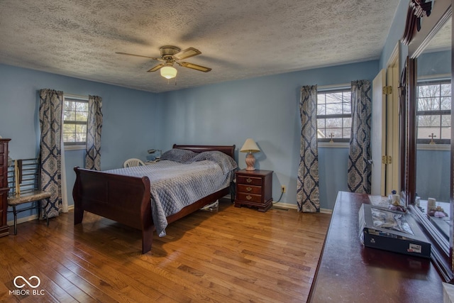 bedroom with multiple windows, ceiling fan, baseboards, and hardwood / wood-style flooring