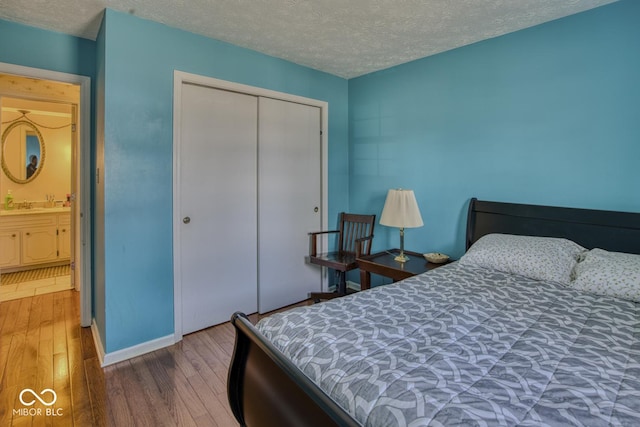 bedroom with a closet, a textured ceiling, and wood finished floors