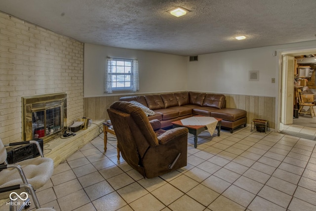 living room with a brick fireplace, a wainscoted wall, visible vents, and light tile patterned floors