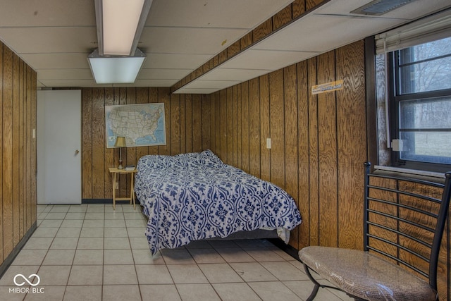 bedroom with wood walls, multiple windows, and light tile patterned flooring