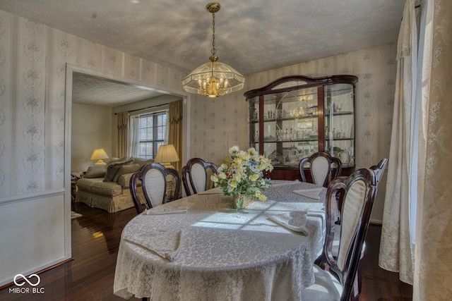 dining area with wood finished floors, a notable chandelier, a textured ceiling, and wallpapered walls