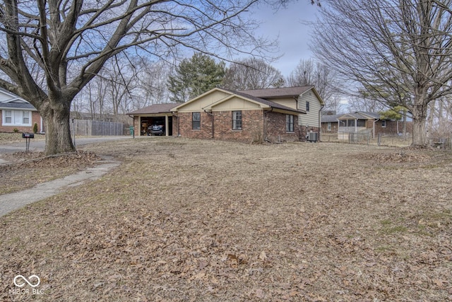 view of front of home featuring brick siding, central AC unit, fence, an attached carport, and driveway