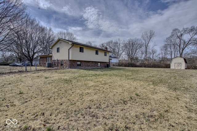 view of side of property with a yard, central air condition unit, a storage shed, fence, and an outdoor structure