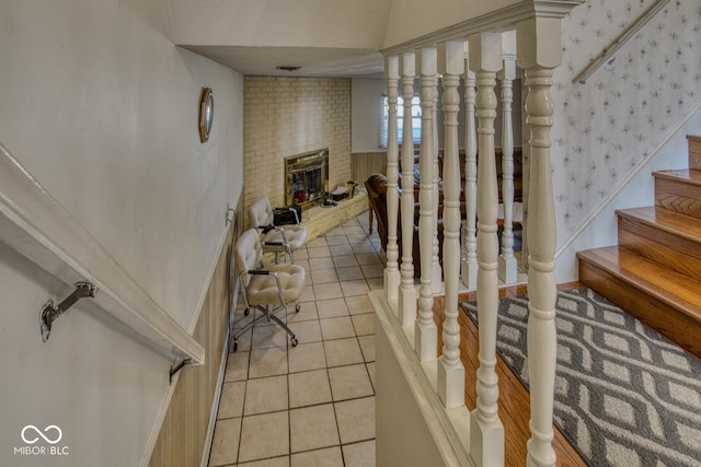 staircase with a brick fireplace, tile patterned flooring, and visible vents