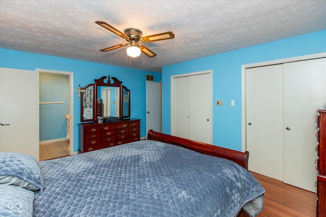 1612 Westbay Ct, Indianapolis, IN 46260 - bedroom with two closets, a textured ceiling, ceiling fan, wood finished floors, and ensuite bath
