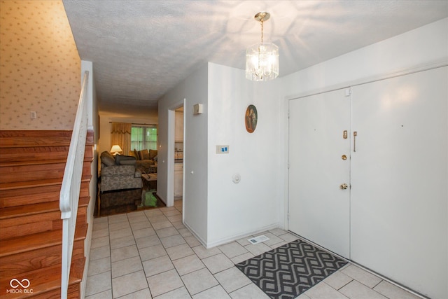 1612 Westbay Ct, Indianapolis, IN 46260 - foyer entrance featuring stairs, a chandelier, light tile patterned flooring, and a textured ceiling