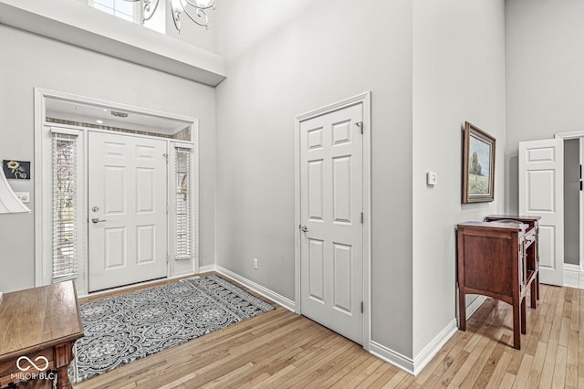 entrance foyer with light wood-style flooring, a high ceiling, and baseboards