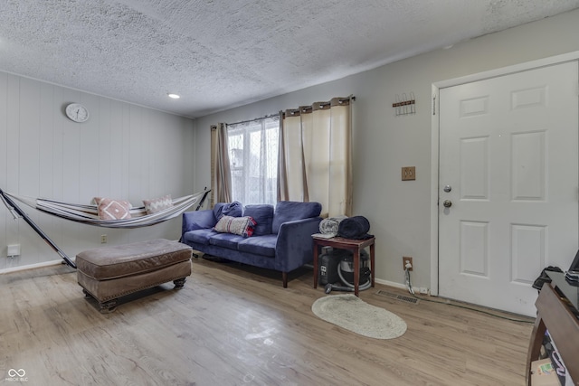 living room featuring a textured ceiling, light wood finished floors, and baseboards