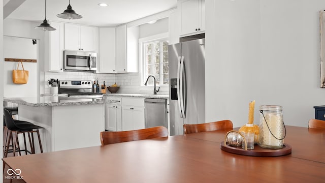 kitchen with a sink, decorative backsplash, appliances with stainless steel finishes, and white cabinetry