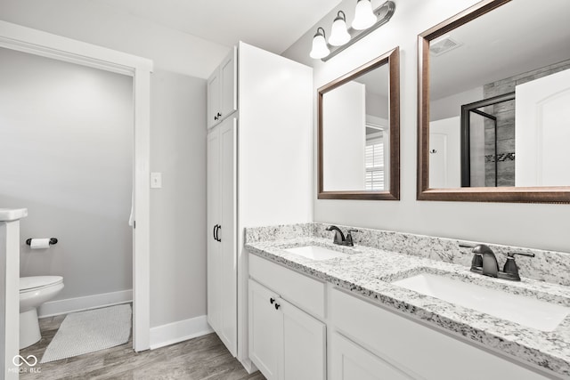 bathroom with a stall shower, baseboards, visible vents, and a sink