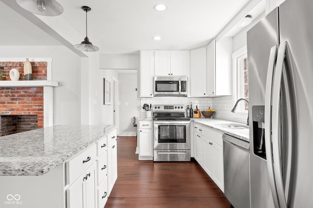 kitchen featuring dark wood-type flooring, a sink, backsplash, appliances with stainless steel finishes, and light stone countertops