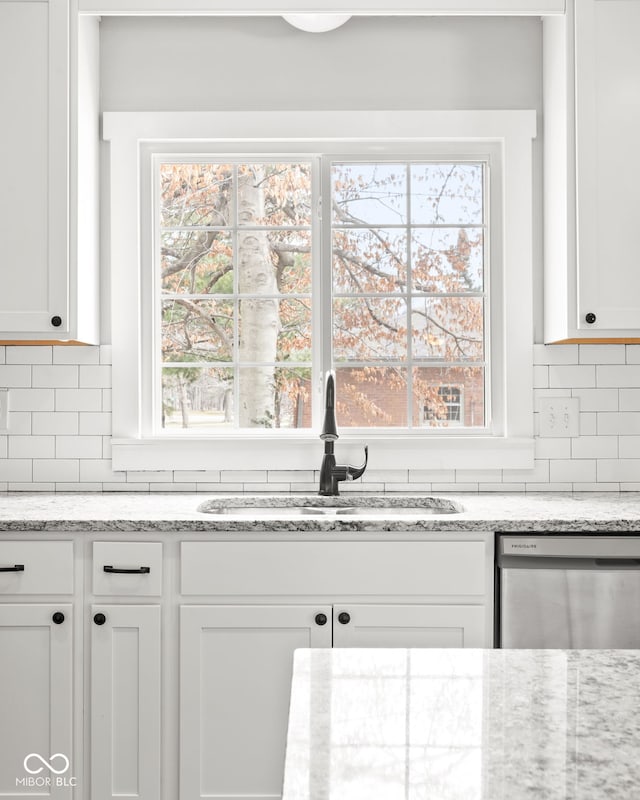 kitchen with dishwasher, tasteful backsplash, white cabinetry, and a sink