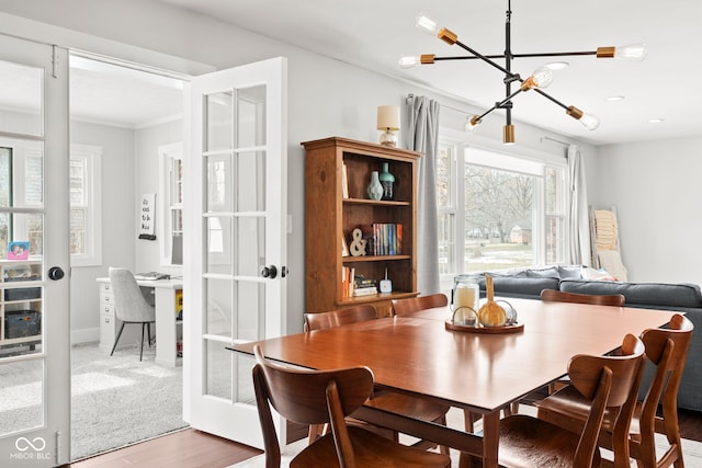 dining space with a notable chandelier, french doors, baseboards, and wood finished floors