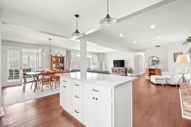 kitchen with hardwood / wood-style floors, light stone counters, open floor plan, and a kitchen island