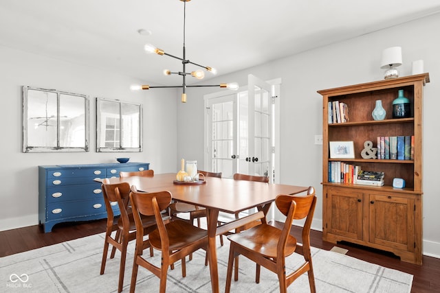 dining room featuring dark wood finished floors, baseboards, and an inviting chandelier