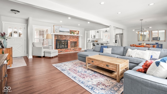 living area with wood finished floors, a notable chandelier, recessed lighting, and a fireplace