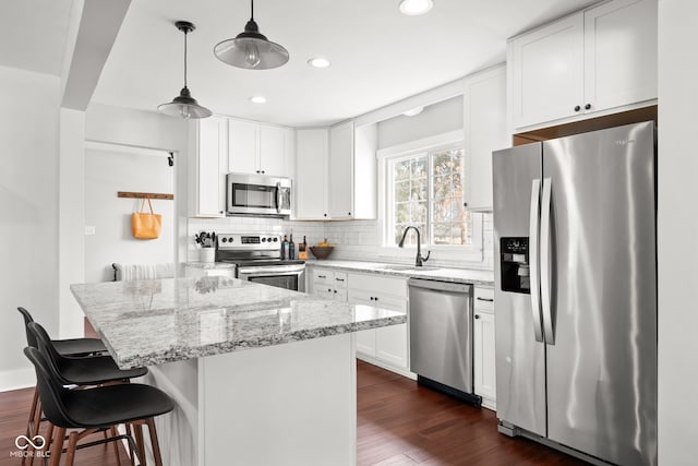 kitchen featuring dark wood-style floors, a sink, decorative backsplash, appliances with stainless steel finishes, and white cabinetry