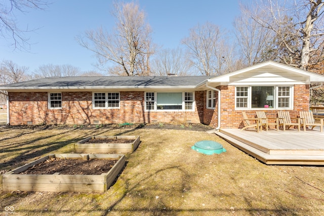 rear view of house featuring a lawn, a deck, a vegetable garden, crawl space, and brick siding