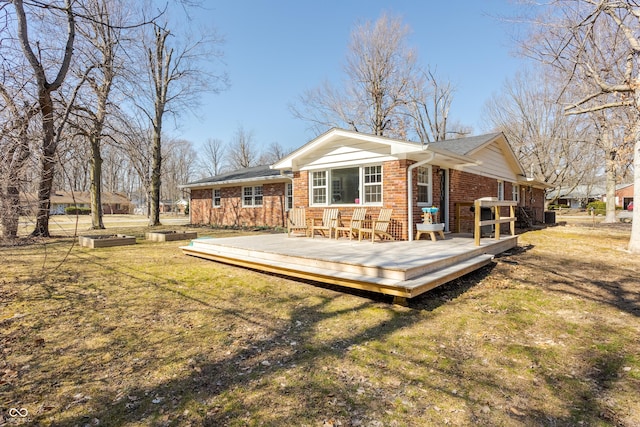 rear view of house featuring brick siding, a deck, and a lawn