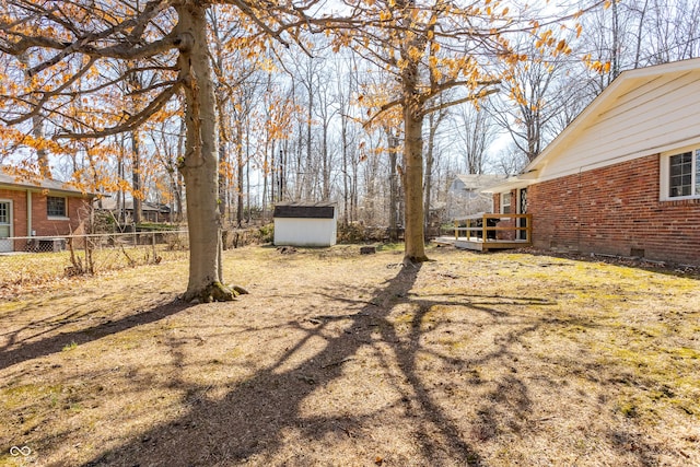 view of yard featuring a deck, a storage shed, fence, and an outdoor structure