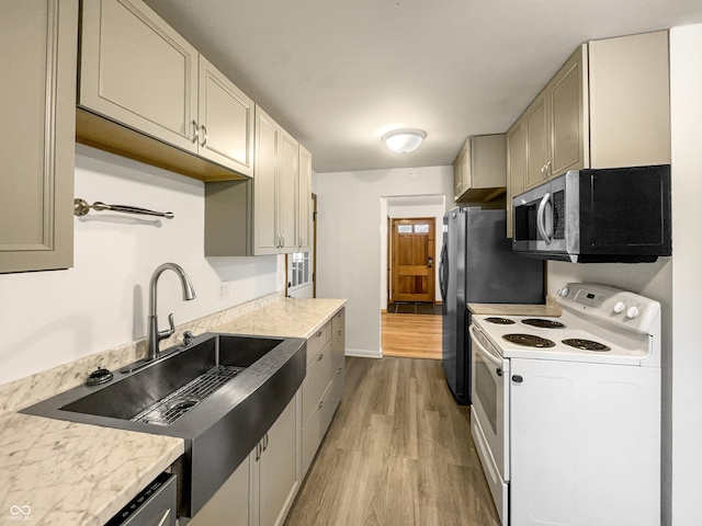 kitchen with electric range, baseboards, stainless steel microwave, light wood-type flooring, and a sink