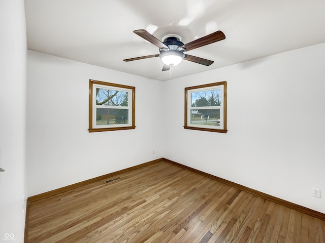 empty room featuring light wood-style floors, baseboards, visible vents, and ceiling fan