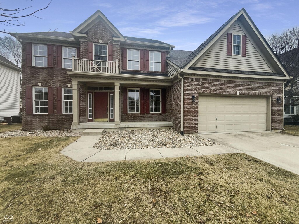 12036 Weathered Edge Dr, Fishers, IN 46037 - view of front of house with brick siding, a porch, a balcony, a garage, and driveway
