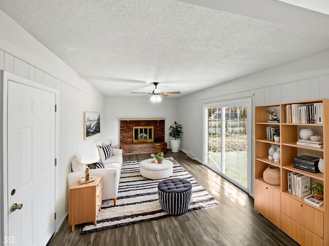 living room featuring a textured ceiling, a fireplace, wood finished floors, and a ceiling fan