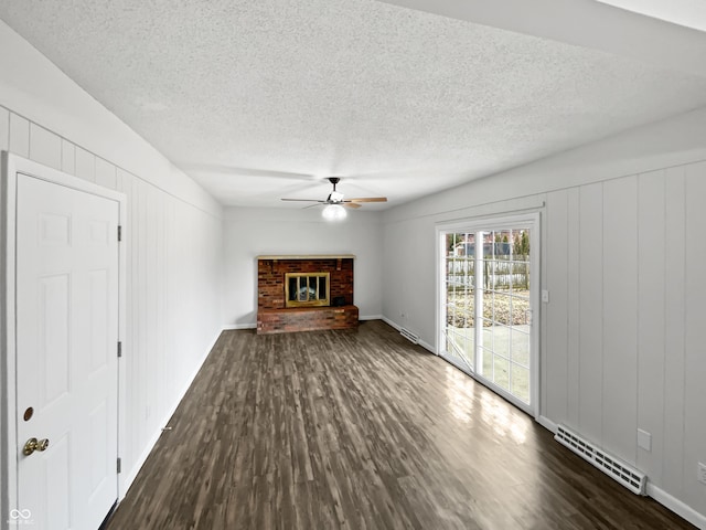 unfurnished living room featuring visible vents, dark wood-style floors, ceiling fan, a textured ceiling, and a fireplace