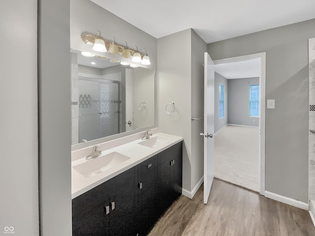 bathroom featuring a stall shower, baseboards, a sink, and wood finished floors