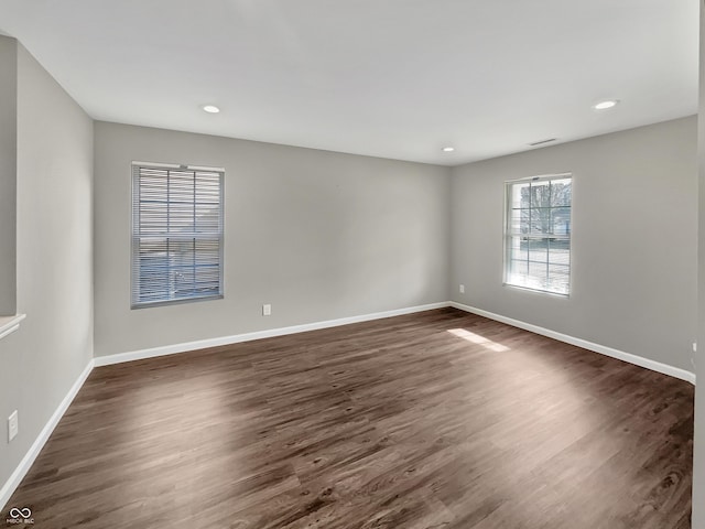 spare room with dark wood-type flooring, recessed lighting, visible vents, and baseboards