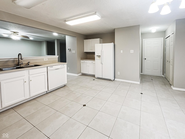 kitchen featuring ceiling fan, light tile patterned floors, white appliances, a sink, and white cabinetry