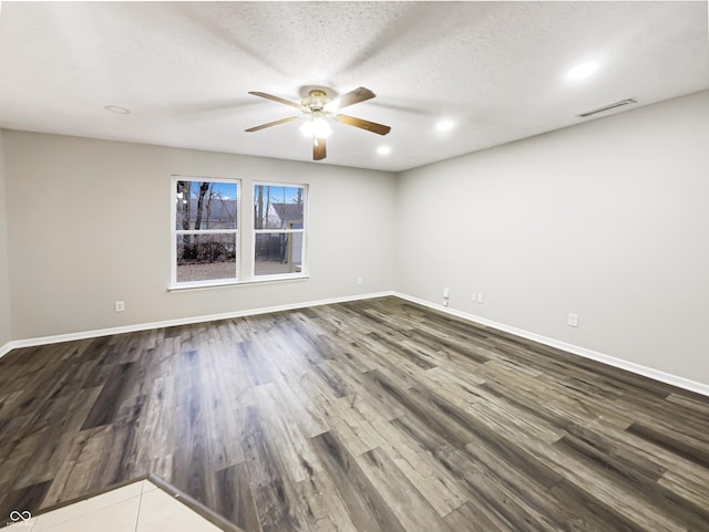 unfurnished room featuring dark wood-type flooring, visible vents, and baseboards