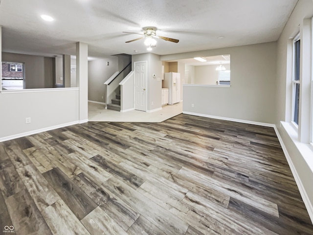 unfurnished room featuring stairs, plenty of natural light, wood finished floors, and baseboards