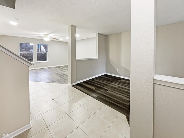 basement with a textured ceiling, baseboards, a ceiling fan, and wood finished floors