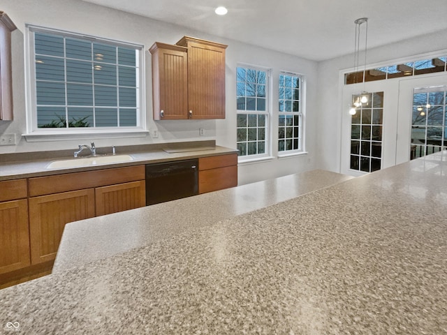 kitchen featuring dishwasher, hanging light fixtures, brown cabinetry, and a sink