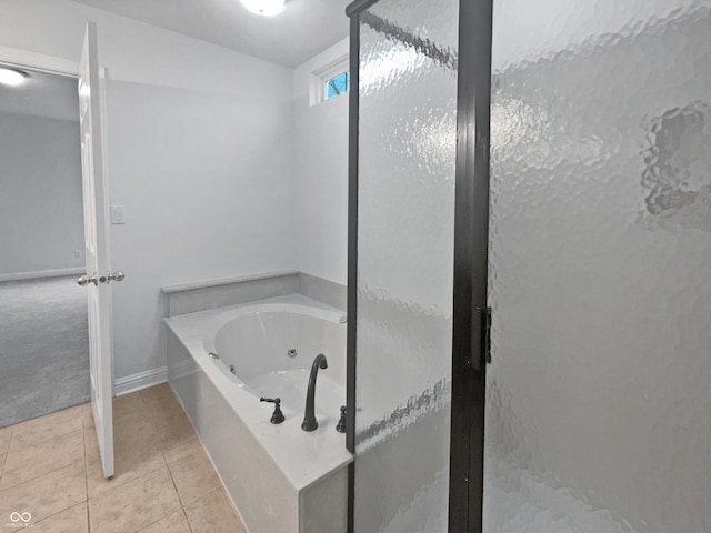 bathroom with a jetted tub, a stall shower, baseboards, and tile patterned floors