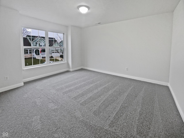 empty room featuring carpet, visible vents, and baseboards