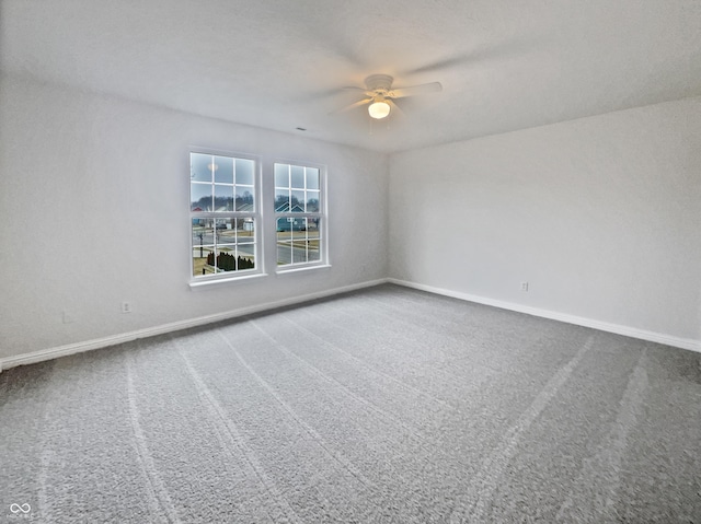 carpeted spare room with a ceiling fan and baseboards