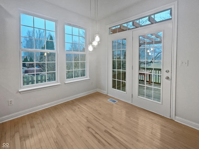 unfurnished dining area with baseboards, visible vents, and hardwood / wood-style floors