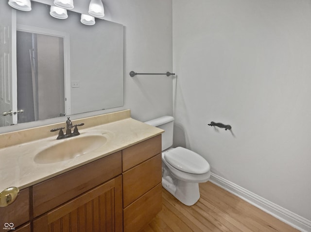 bathroom featuring wood finished floors, vanity, toilet, and baseboards