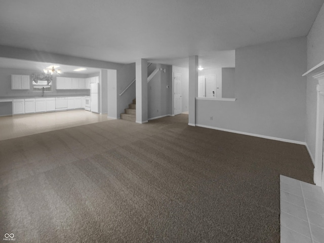 unfurnished living room featuring baseboards, stairway, a tiled fireplace, and light colored carpet