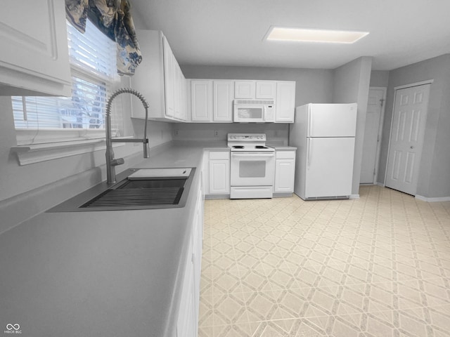 kitchen featuring light floors, light countertops, white cabinetry, a sink, and white appliances