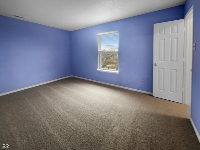 carpeted spare room with visible vents and baseboards