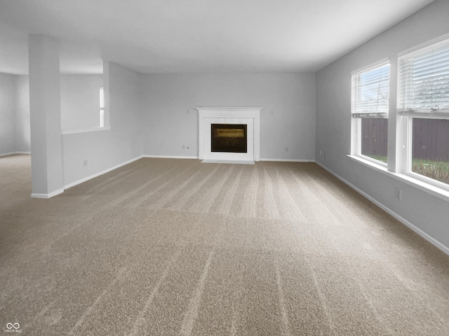 unfurnished living room with carpet, a glass covered fireplace, and baseboards