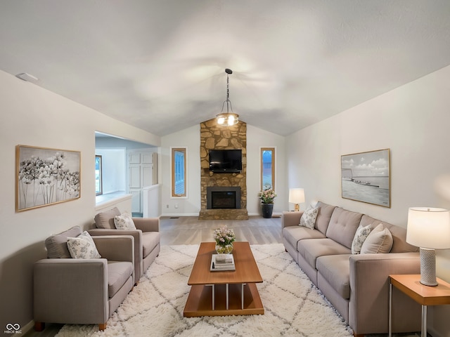 living room featuring lofted ceiling, a stone fireplace, baseboards, and wood finished floors