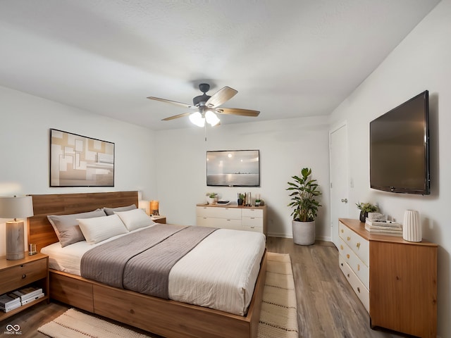 bedroom with ceiling fan, wood finished floors, and baseboards