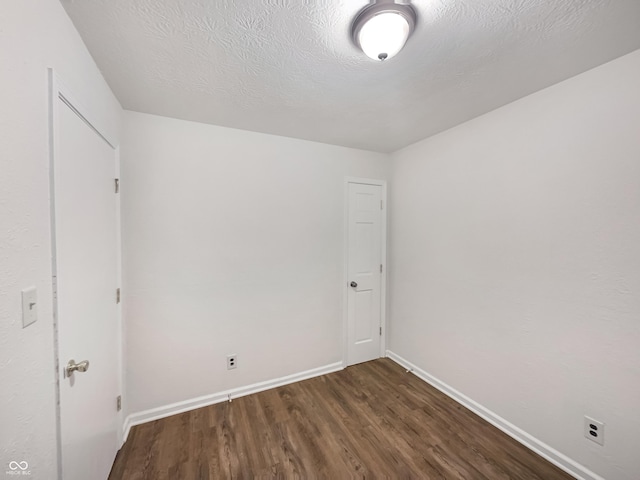 unfurnished room featuring a textured ceiling, baseboards, and wood finished floors