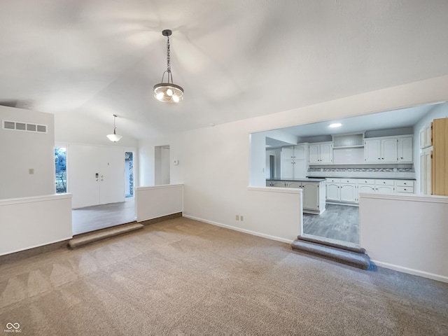 interior space featuring carpet, visible vents, vaulted ceiling, and baseboards